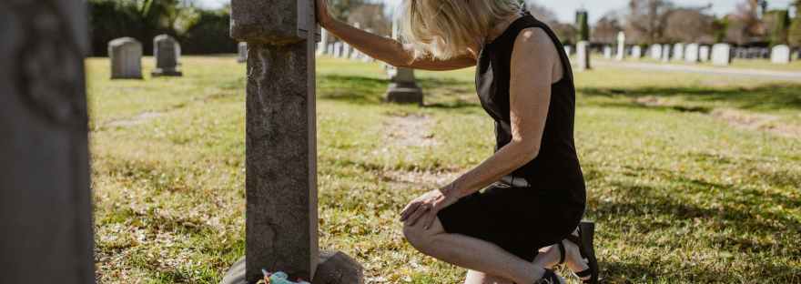 photo of woman kneeling in front of gravestone